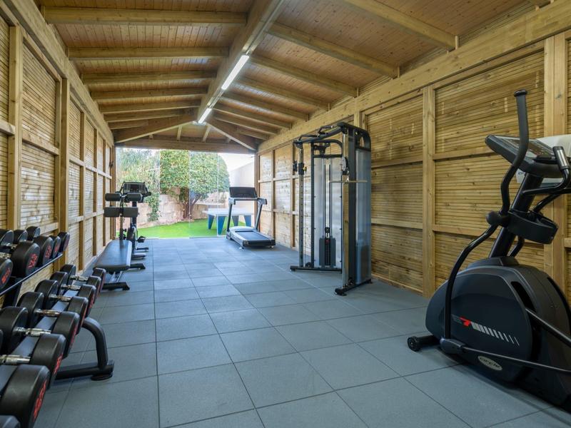 Wnętrze drewnianej siłowni z urządzeniami do ćwiczeń i hantlami w hotelu wellness