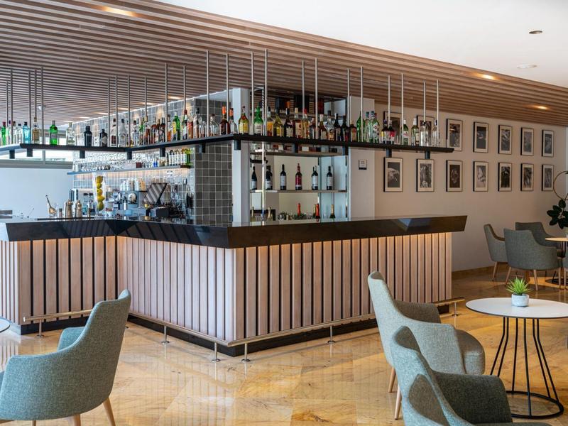 Nowoczesny bar hotelowy z drewnianym kontuarem, półkami i wygodnymi fotelami