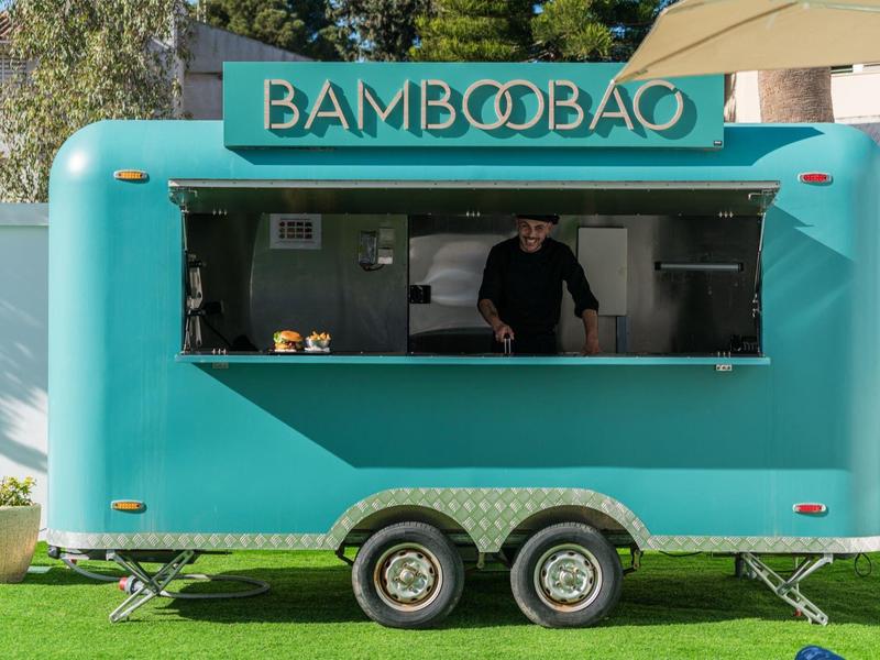 Turkusowy food truck z napisem BAMBOOBAO i osobą w środku.
