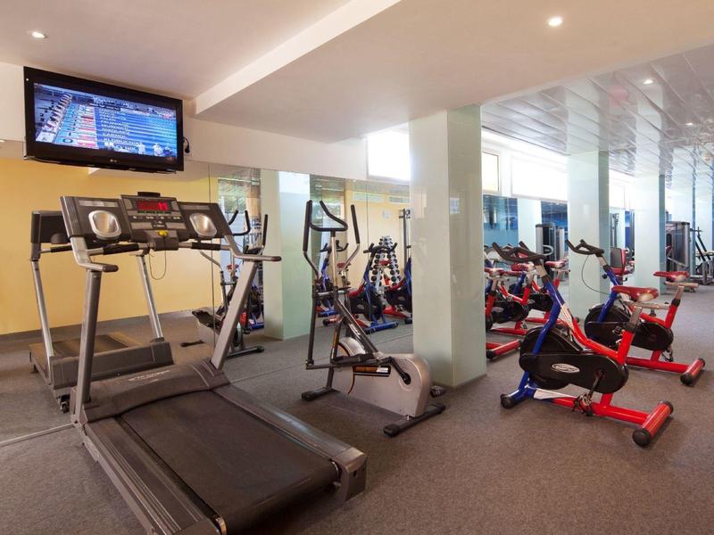 Moderní fitness vybavení v jasném a prostorném hotelovém fitness centru s velkými zrcadly.