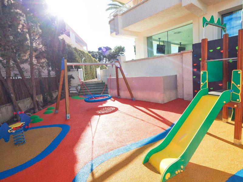 Barevné hřiště s klouzačkou a houpačkou vedle moderní budovy.