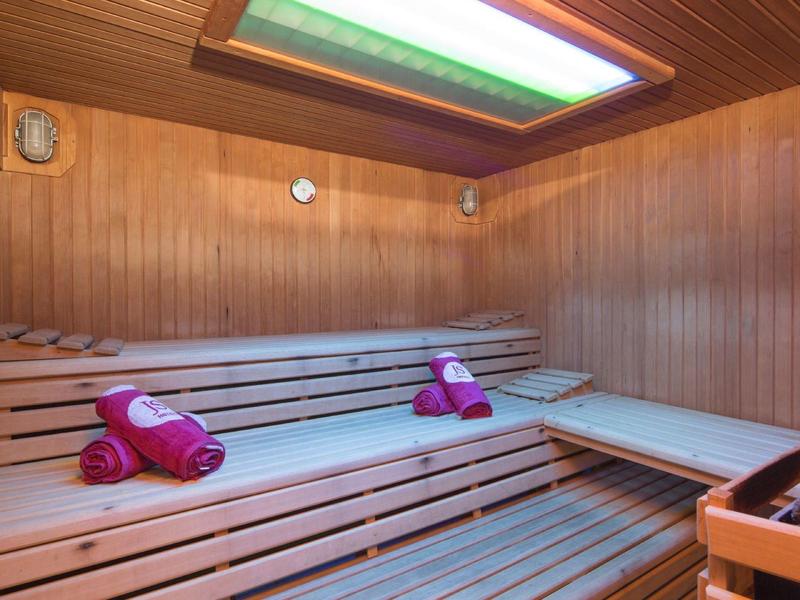 Dřevěná sauna s víceúrovňovými lavicemi a srolovanými růžovými ručníky.