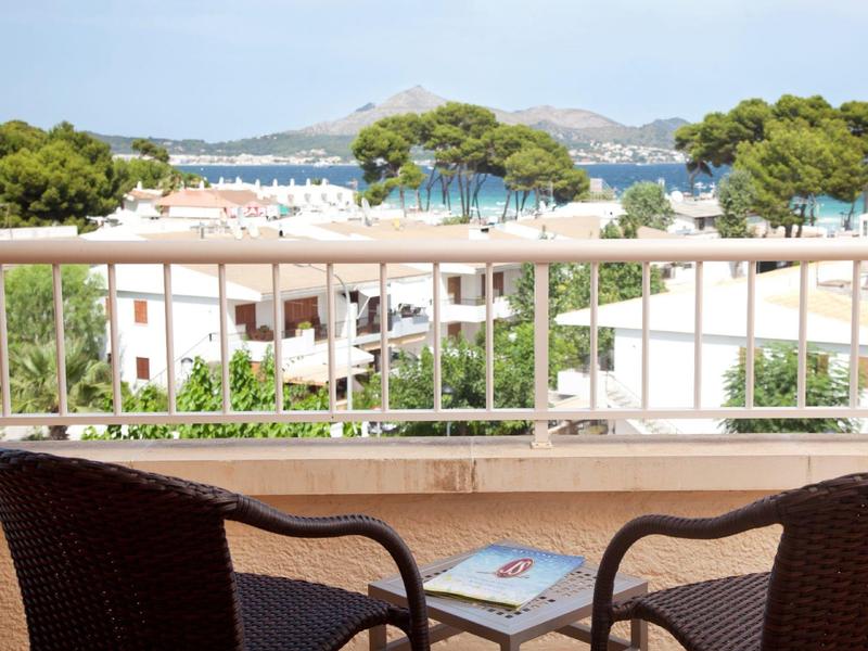 Balkon se dvěma židlemi a výhledem na moře za jasné oblohy.