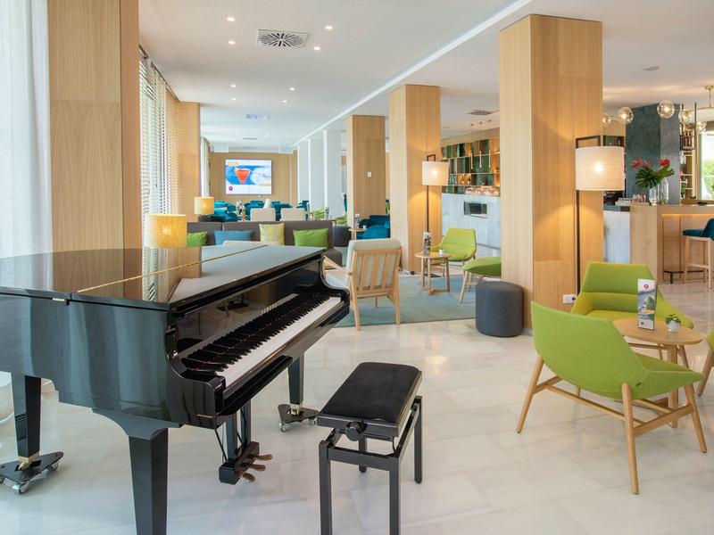 Moderní hotelová lobby s koncertním křídlem, pohodlným posezením a světlými dřevěnými doplňky.