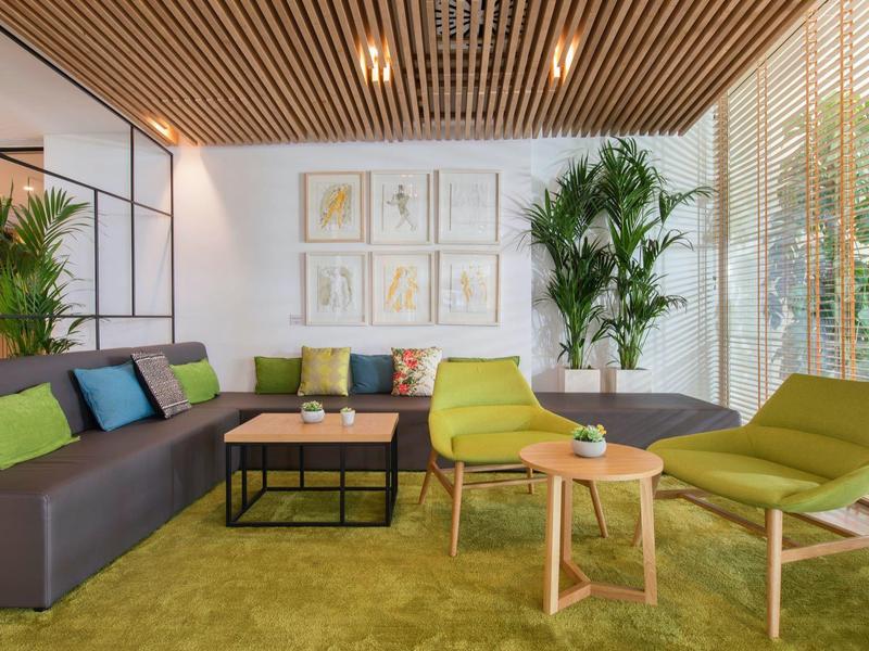 Moderní a útulný obývací pokoj s posezením, rostlinami a dřevěným stropem.