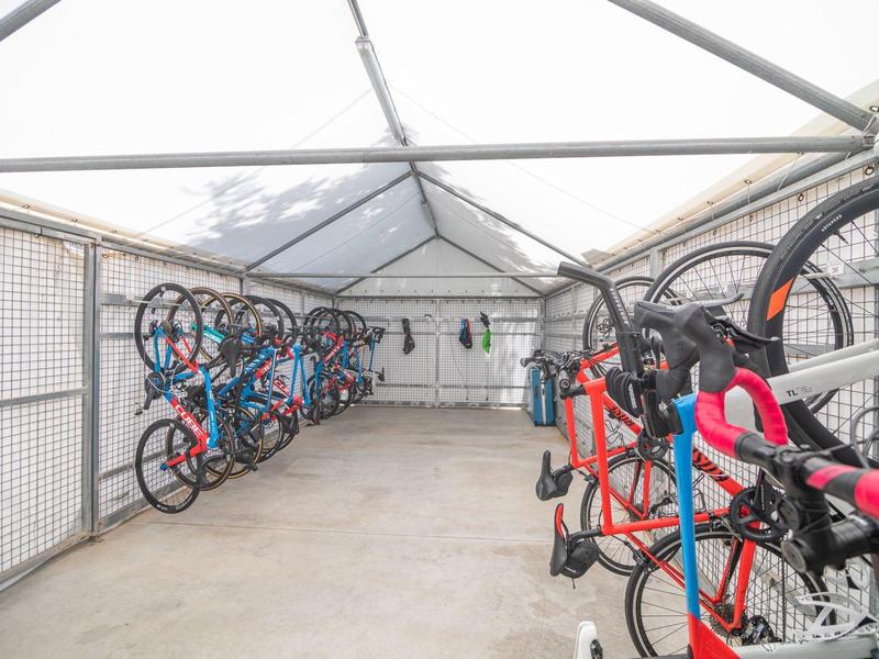 Zastřešená místnost na kola s několika jízdními koly zavěšenými na stěnách.
