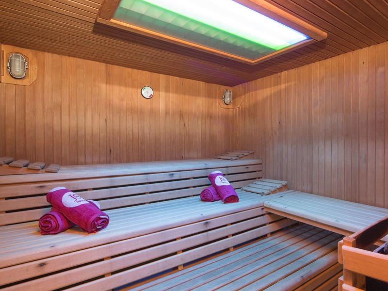 Dobře osvětlená sauna s dřevěným obložením a růžovými ručníky.