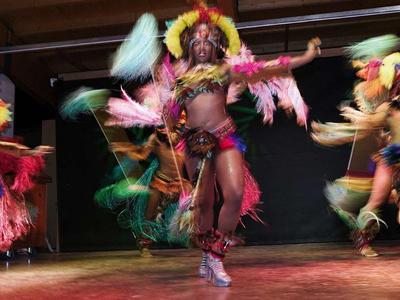 Tres bailarines con disfraces coloridos realizan una danza animada en un escenario.