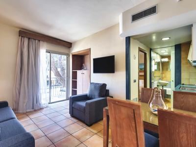 Světý obývací pokoj s pohovkou, křeslem, jídelním stolem, balkonem a vybavenou kuchyní.