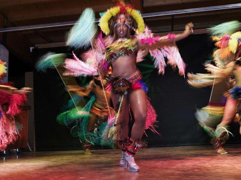 Tanečníci v barevných kostýmech předvádějí živý tanec na pódiu.