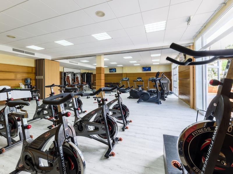 Palestra moderna con diverse cyclette e pesi in una stanza luminosa.