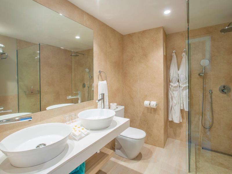 Bagno moderno con doppio lavabo, WC e doccia a filo in tonalità calde.