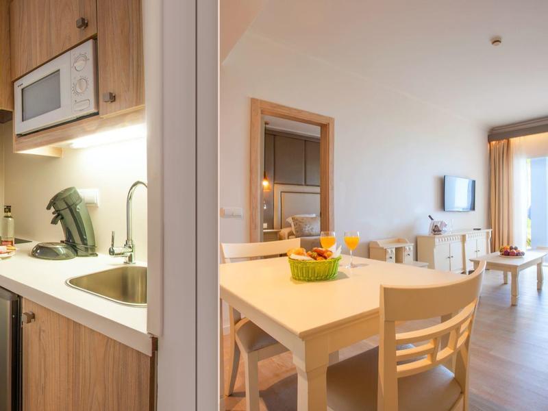 Appartamento per vacanze luminoso e moderno con angolo cottura, zona pranzo e soggiorno con divano e TV.