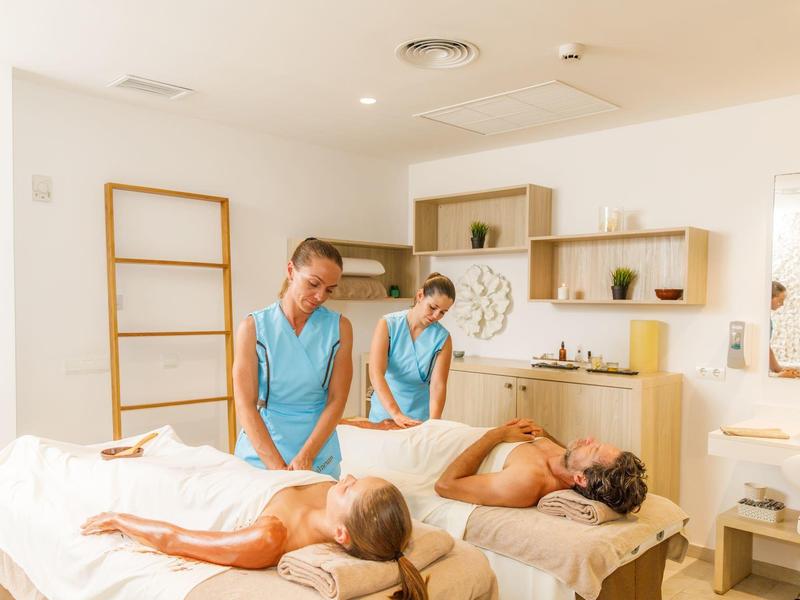 Due donne ricevono contemporaneamente un massaggio alla schiena in una spa luminosa e moderna.