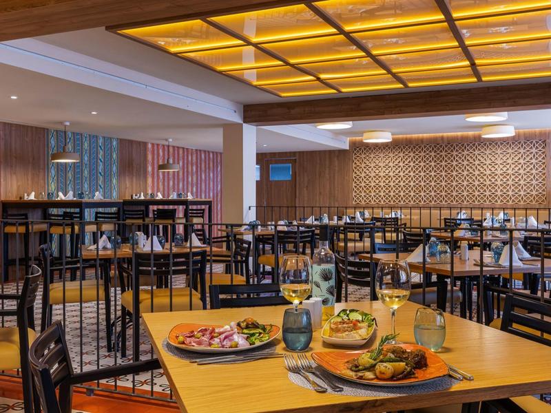 Area ristorante moderno dell'hotel con tavoli apparecchiati e luce calda al soffitto