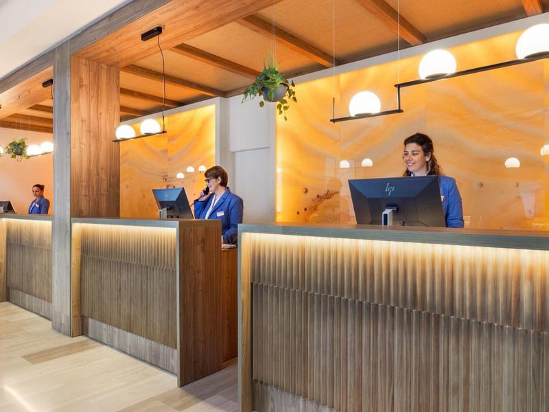 Reception dell'hotel con più dipendenti che lavorano alle scrivanie con computer.
