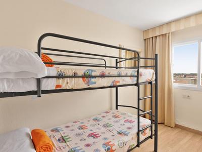 Zweistöckiges Bett in einem hellen, einfachen Zimmer mit großem Fenster und Blick auf Stadt.