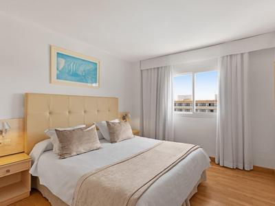 Helles Schlafzimmer mit Doppelbett, beigen Vorhängen, Holzboden und Wandbild an der Wand.