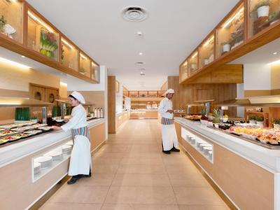 Zwei Köche in einer geräumigen, modernen Buffetküche mit hellem Holz und verschiedenen Speisen.