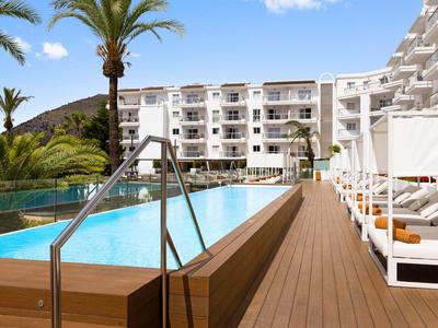 Piscina moderna dell'hotel con lettini e palme sotto il cielo azzurro