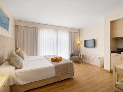 Modernes Hotelzimmer mit Doppelbett, hellem Holzfußboden und einem kleinen Essbereich.