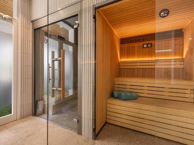 Moderner Sauna-Raum mit Holzverkleidung und Glastür in einem Wellnessbereich.