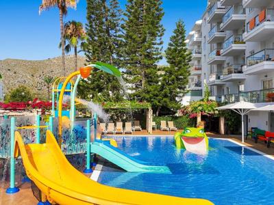 Hotelpool mit Wasserrutschen, Sonnenschirmen und umgeben von mehrstöckigen Gebäuden und Bäumen