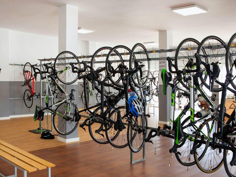 Innenraum mit mehreren Fahrrädern, die an einer Halterung aufgehängt sind, Holzboden und Sitzbank