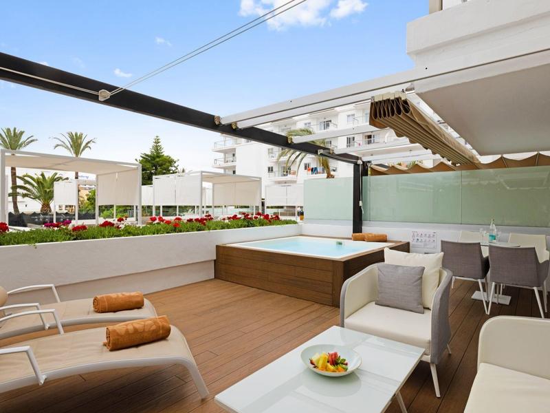 Moderne Terrasse mit Liegestühlen, Whirlpool, Esstisch und Blick auf eine Poollandschaft.