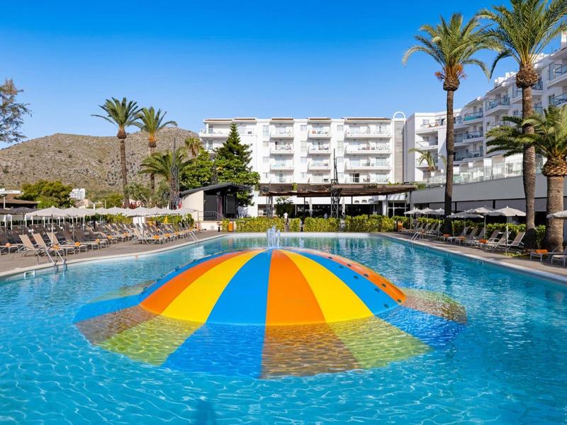 Hotelpool mit buntem Wasserspiel und Liegestühlen in sonniger Umgebung