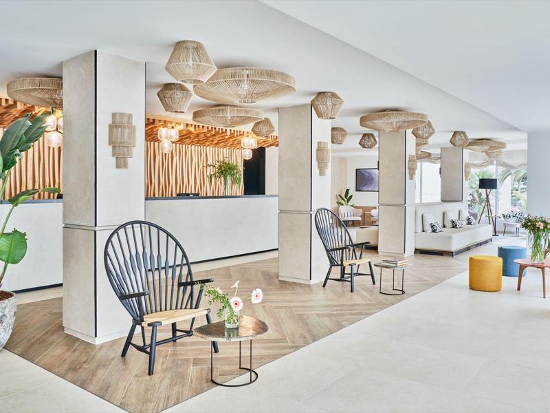 Moderní hotelová hala s ratanovými křesly, stolky a světlou výzdobou.