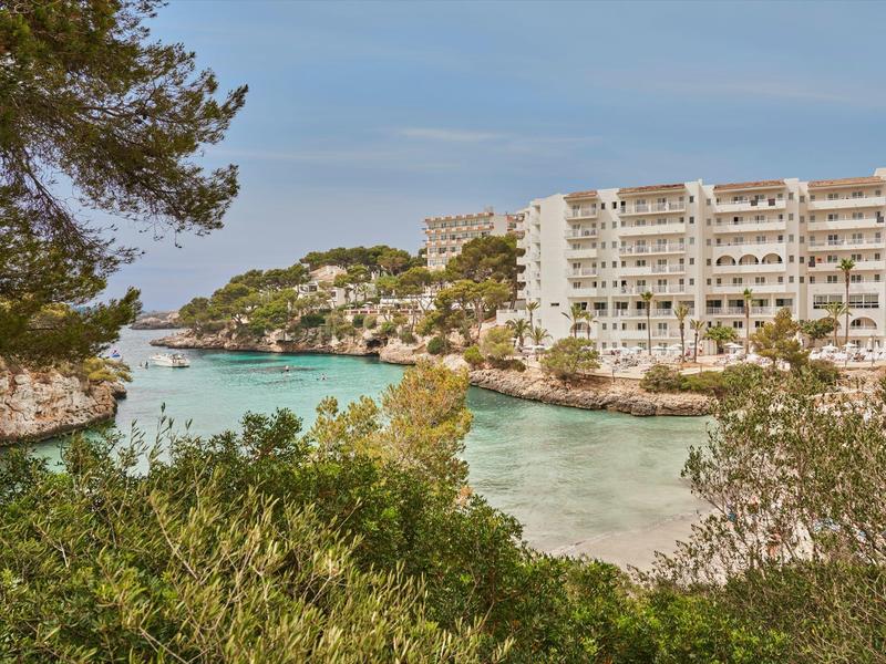 Moderní hotel u zátoky s tyrkysovou vodou obklopený bujnou vegetací.