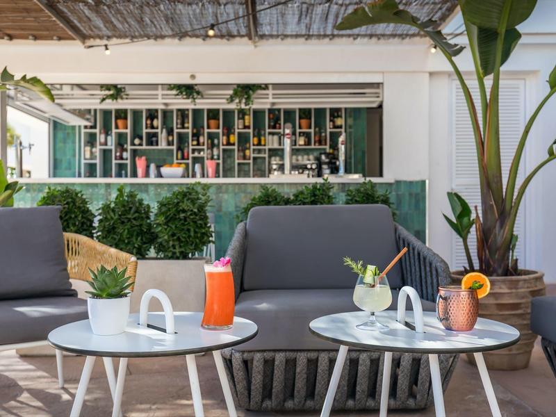 Terasa hotelu se šedými křesly, bílými stoly a osvěžujícími nápoji.