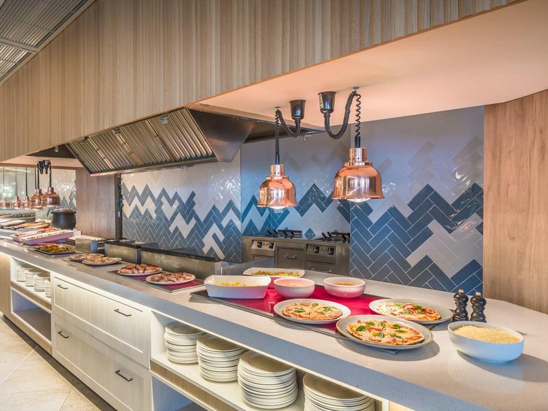 Moderní bufet s pizzami a ohřívači talířů v hotelové restauraci.