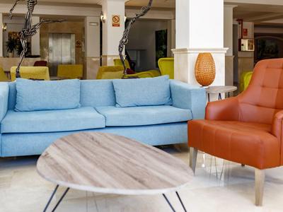 Coin salon confortable avec canapé bleu, fauteuil marron et table en bois ovale.