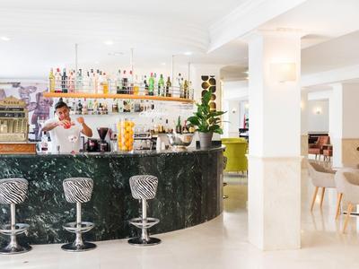 Espace bar d'hôtel moderne avec bar élégant, tabourets et ambiance lumineuse.