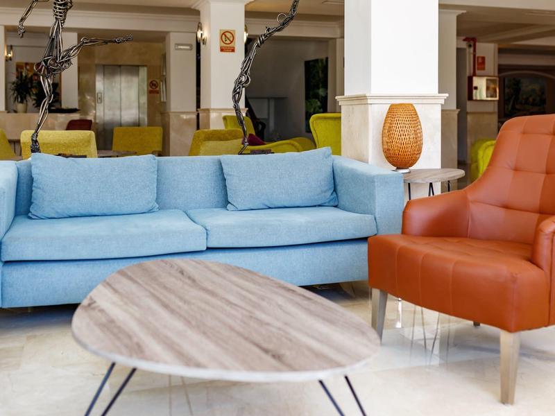 Coin salon confortable avec canapé bleu, fauteuil marron et table en bois ovale.