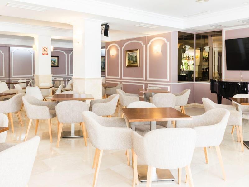 Salle à manger lumineuse et moderne avec chaises blanches et tables en bois dans un hôtel.