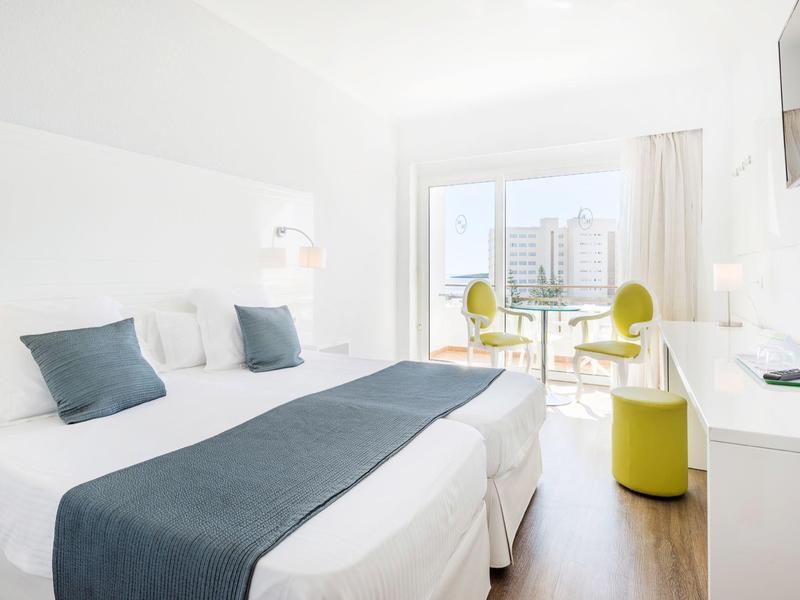 Chambre d'hôtel moderne avec deux lits simples, balcon et vue sur la ville.