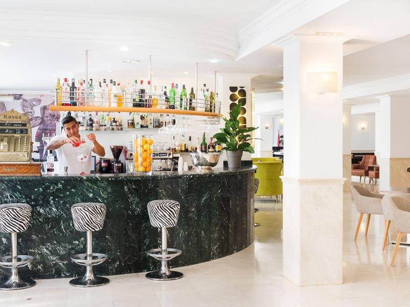 Espace bar d'hôtel moderne avec bar élégant, tabourets et ambiance lumineuse.