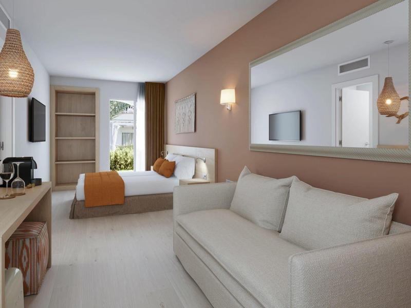 Moderní hotelový pokoj s pohodlnou pohovkou, postelí a teplými zemními tóny.