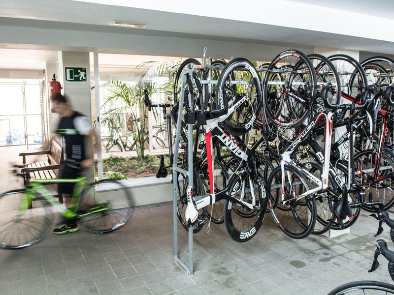 Fahrräder hängen an einer Wand in einem Fahrradkeller mit verschwommenem Radfahrer im Vordergrund.