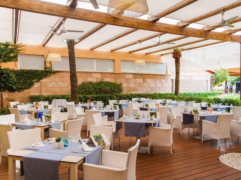 Überdachte Außenlounge mit modernen Tischen und Stühlen auf Holzterrasse