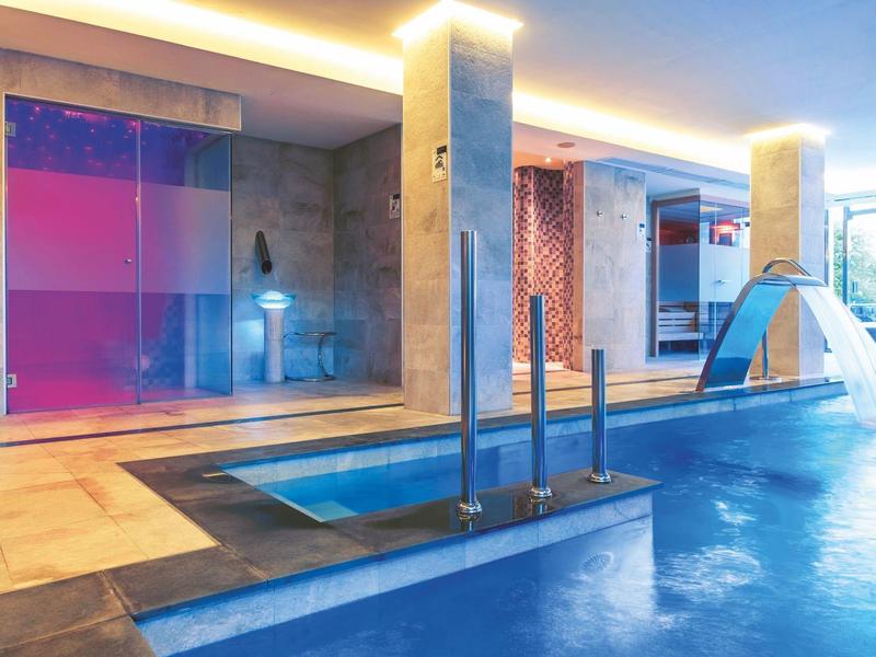 Moderner Wellnessbereich mit Schwimmbad, Sauna, Wasserrutsche und stilvoller Beleuchtung.