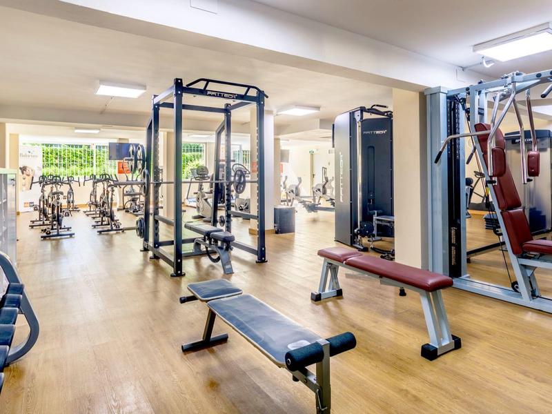 Helles Fitnessstudio mit Laufbändern, Gewichten und Trainingsgeräten auf Holzboden.