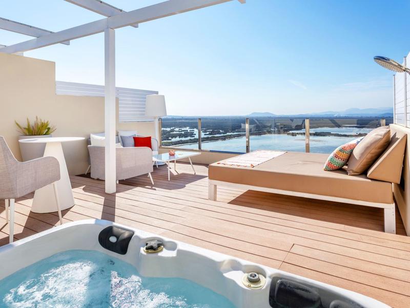 Moderne Dachterrasse mit Whirlpool, Sitzbereich und Panoramaausblick bei klarem Himmel