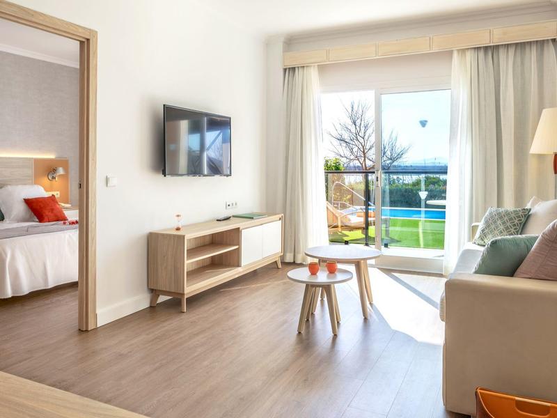 Modernes Wohnzimmer mit Sofa, Fernseher und großem Fenster mit Blick auf Garten