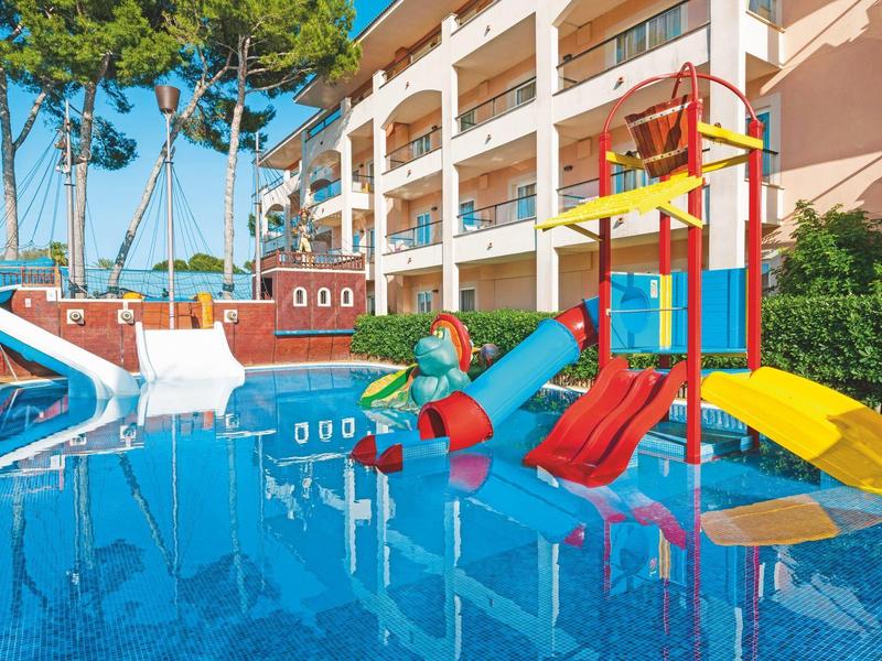 Hotelpool mit Wasserrutschen und Klettergerüst vor mehrstöckigem Gebäude