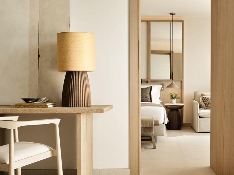 Nowoczesne pokoje z minimalistycznym drewnianym designem i neutralnymi kolorami, z widokiem na dwa łóżka.