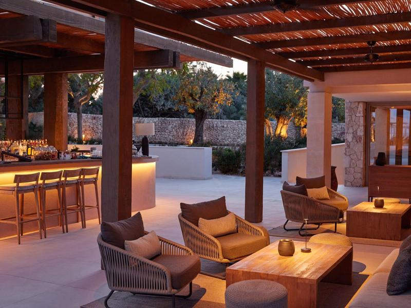 Przytulny zewnętrzny bar hotelowy z nowoczesnym oświetleniem i miejscami do siedzenia o zachodzie słońca.